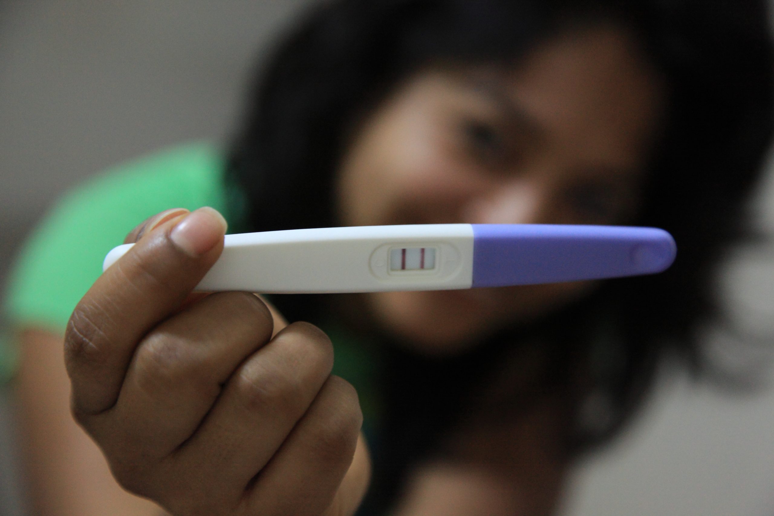 A woman holds up a positive pregnancy test.