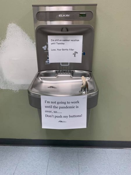 A sign hangs on a water fountain at Lumen Christi High School in Anchorage that says: "I'm not going to work until the pandemic is over, so.... Don't push my buttons!"