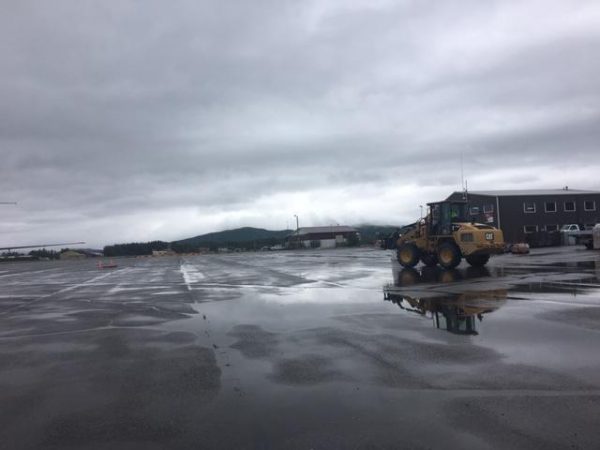 A loader in a puddly asphalt runway