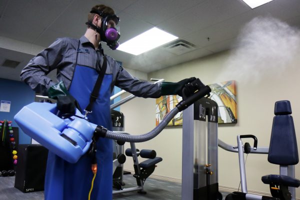 Joshua Easterly, operations manager at Alaska Club East, uses a disinfectant fogger to clear the gym.