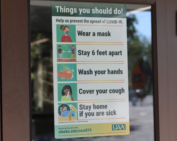 A sign on the door at the University of Alaska Anchorage Student Union instructs people to wear a mask, stay 6 feet apart, wash their hands, cover their coughs and stay home if sick.