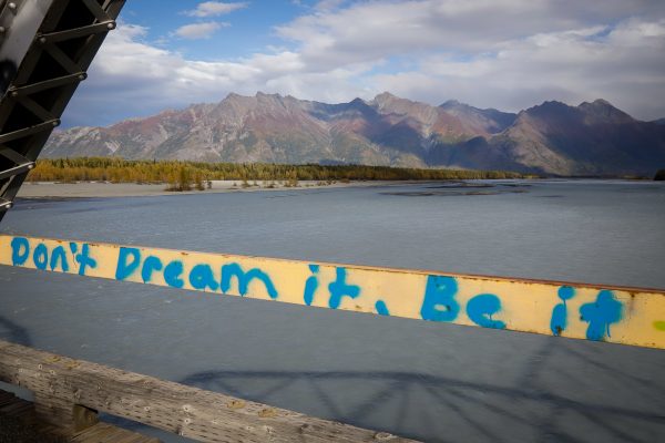 A message that reads "don't dream it, be it" in front of mountains and water