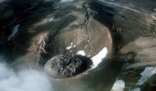 An aerial view of a crater with an  unusual rock formation in the middle that looks like oozing lava