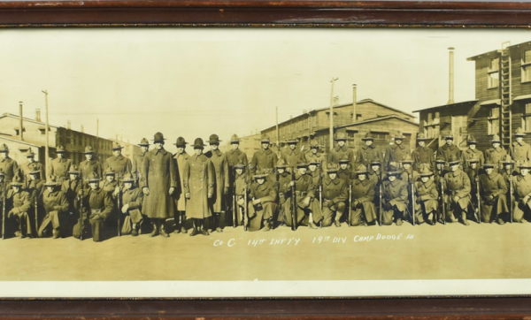A black and whihte photo showing about 30 infantryment kneeling with rifles