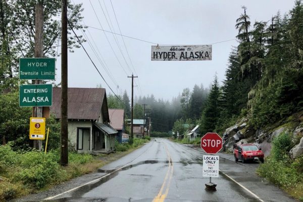A stop sign on a small road with wooden buildings and rain on the