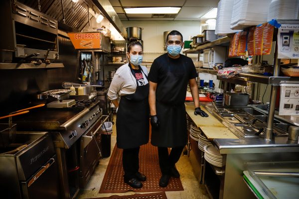 two people stand in a restaurant kitchen