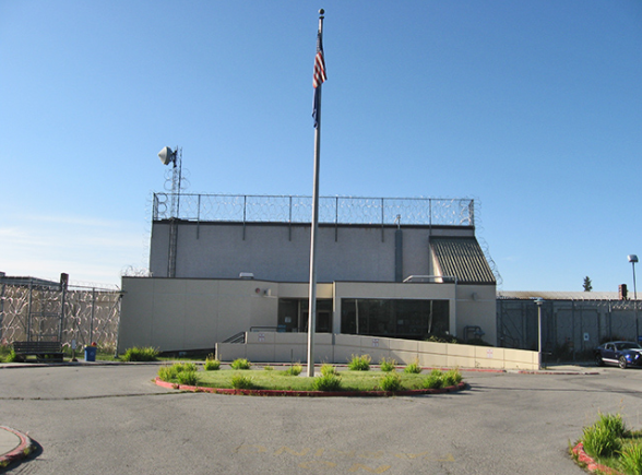 A plain looking building with a flag pole in front
