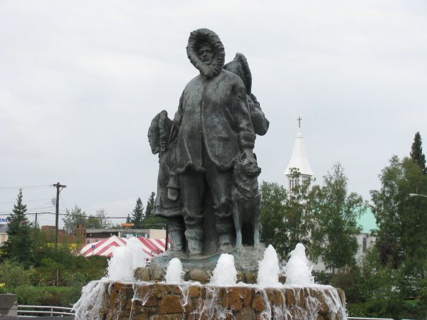 A statue of a man in a parka next to two others.