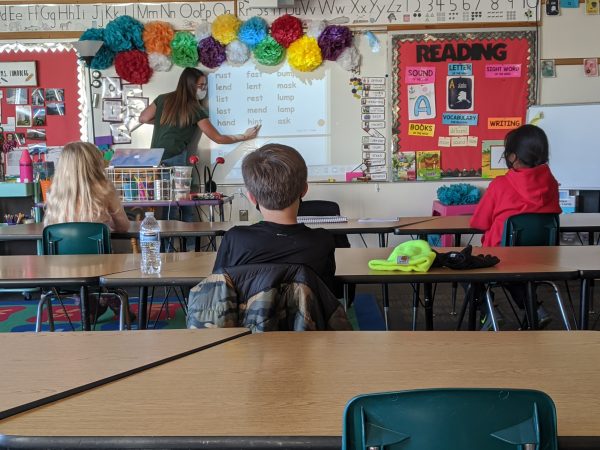 An Anchorage teacher points to a word projected on a white board in a classroom, with three students sounding out words during an after-school tutoring program. 