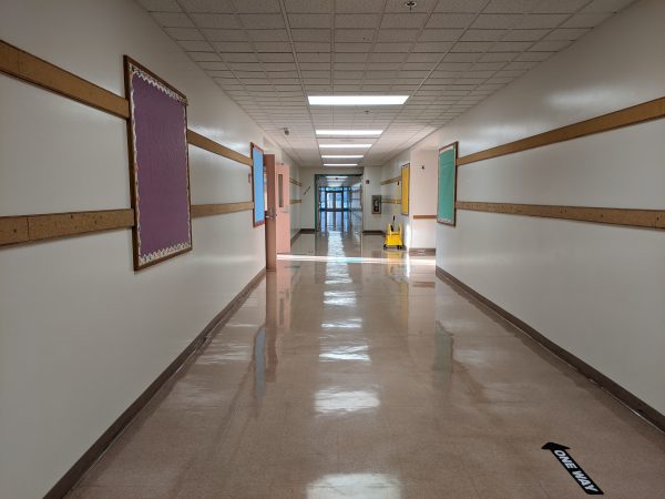 An empty hallway with a display board with a purple backgrond on the left wall