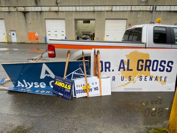 Campaign signs rest upside down against a white pickup truck