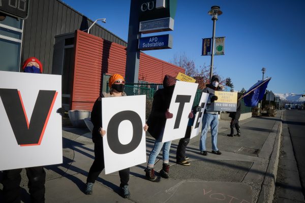people hold up signs that spell out "VOTE"