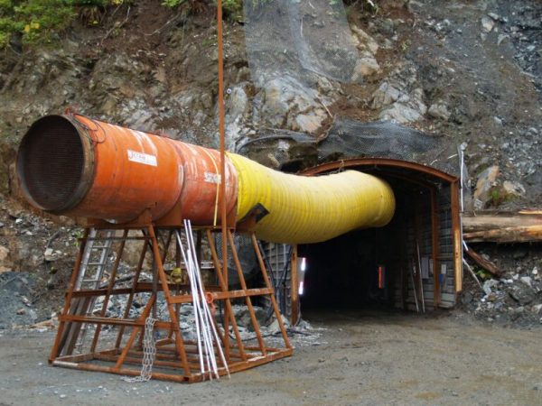 A tube comes out of a hole in a mountainside
