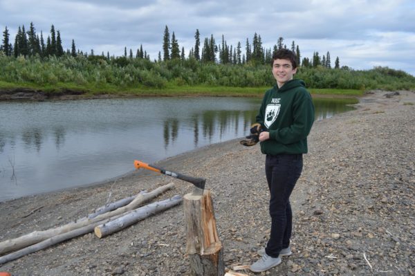 A young man from the Northwest Arctic, who attends Harvard and was recently accepted as a Rhodes Scholar, stands by the Kobuk River.