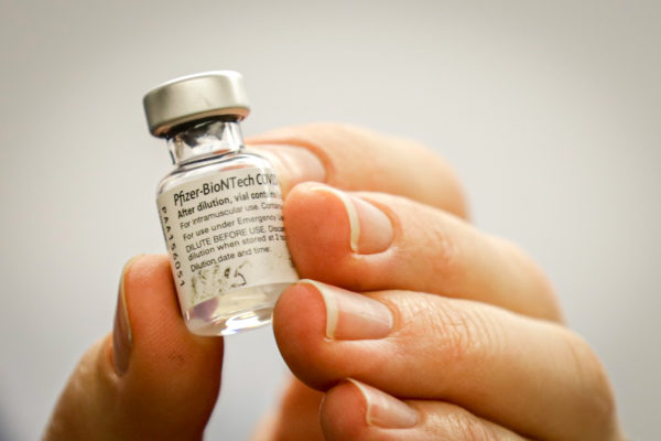 a person holds a vial of the COVID-19 vaccine