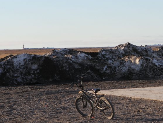 A bicycle parked with oil rigs visible in the backfroung