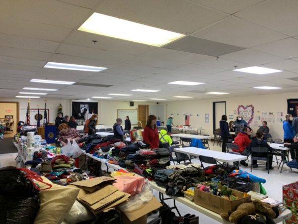 Tables filled with emergency clothes and supplies in a low-ceilinged room