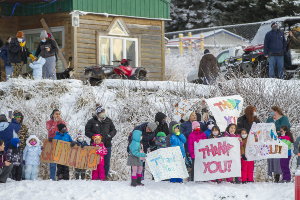 A group of residents hold signs in a snowy scene that say thank you