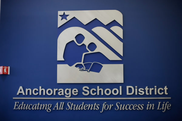 the logo and text on wall that reads "Anchorage School District -- Education All Students for Success in Life"