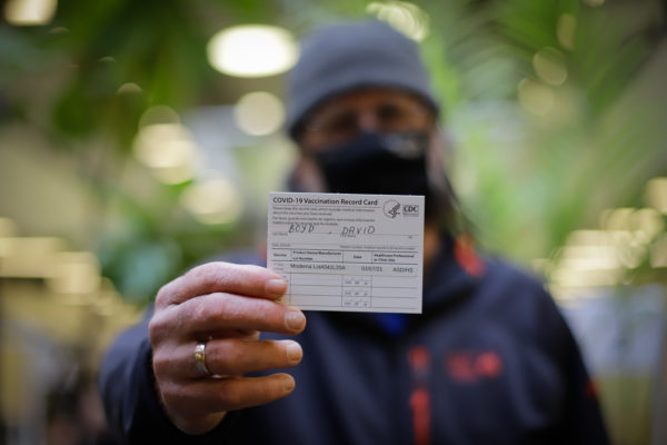 a person holds a Covid-19 vaccination record card