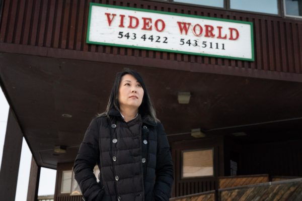 A Korean woman stands in front of a sign for video world