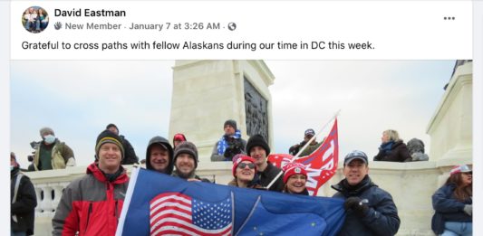 People stand on marble steps outdoors with flag that says "Alaska for Trump"
