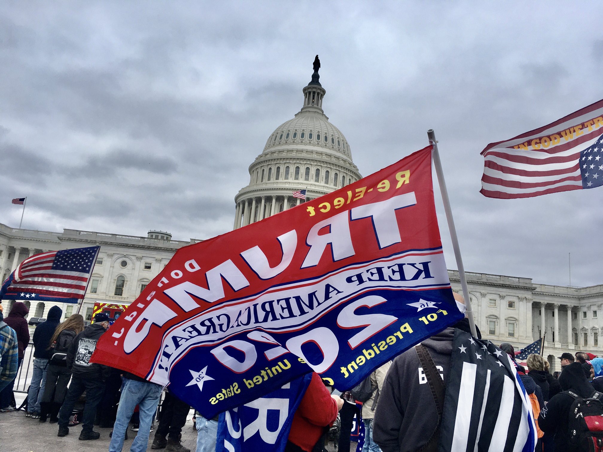 A large Trump flag waves in front of the U.S. Capitol