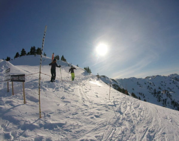 Skiers carry skies on the snow slope on a  sunny day
