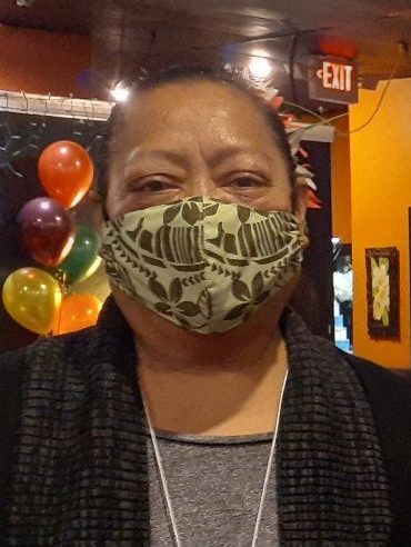A Samoan woman wearing a mask at a party with balloons in the background