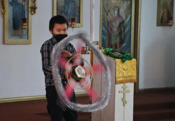 A boy spins a star shaped spinner inside a church wearing a mask
