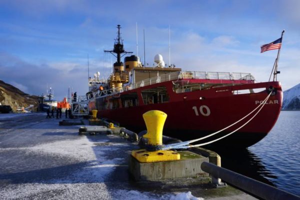 An ice breaker sits at a dock with a ling from the bow