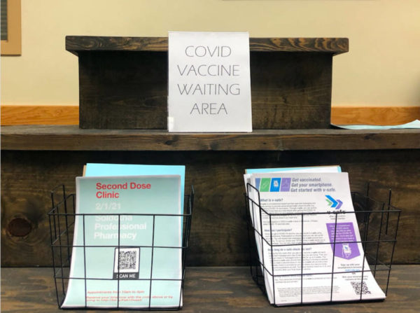 A podium with a piece of paper taped up saying 'covid vaccine clinic'