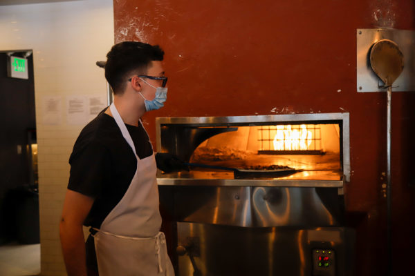 Pizza cooks in a wood-fired oven.