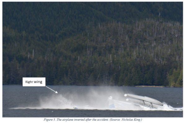 An overturned float plane in front of a mountain side