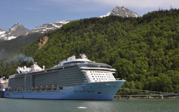A cruise ship next to a forested hill