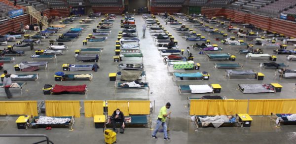 Cots laid out on an arena floor