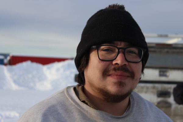 A man in thick rimmed glasses and a beanie