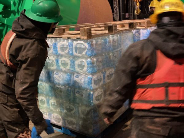 Workers load a pllete of water pbottles