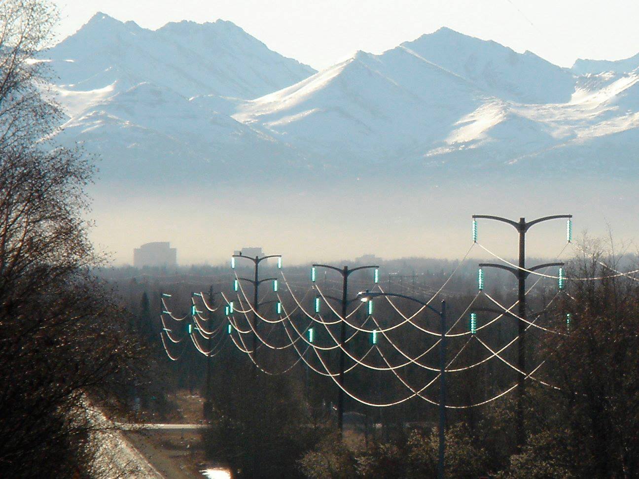 Power transmission lines on poles in the foreground, with mountains in the distance.