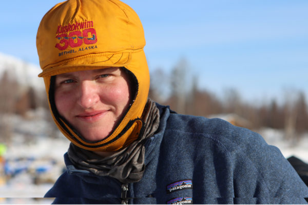A woman smiles wearing a winter hat that says Kuskokwim 300 on it.