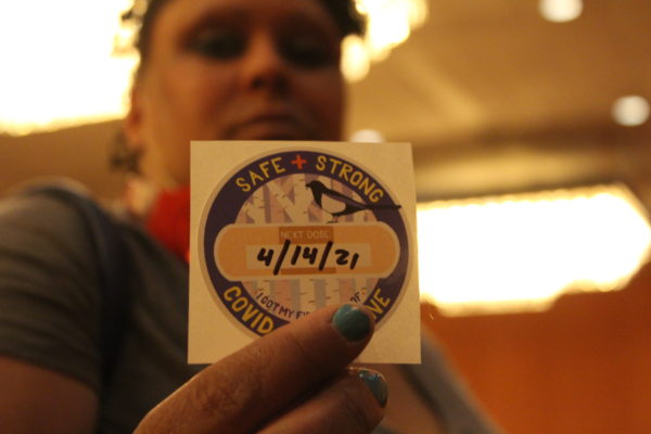 A person shows a sticker showing they got a first dose of the COVID-19 vaccine