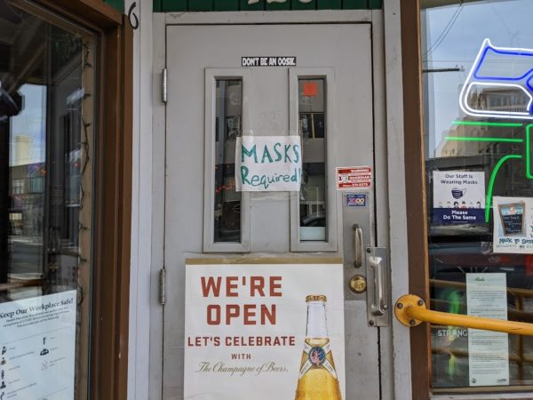 An entrance to a bar with 'masks required' written in