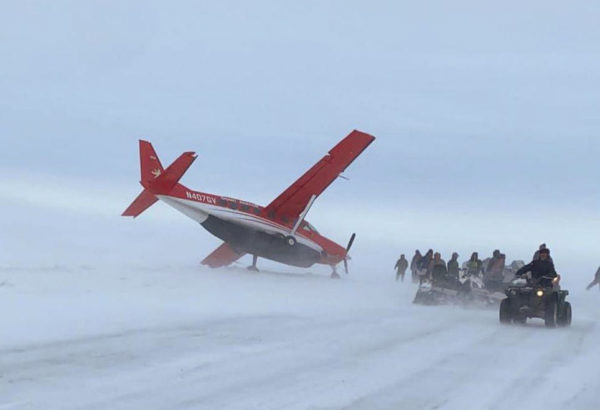 A plane in a blizzard leaning on one wing