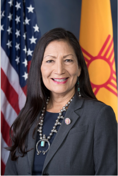 A Native American woman smiling in front of a US and New Mexico flag