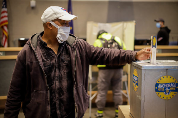 a person drops a ballot into a secure ballot box.