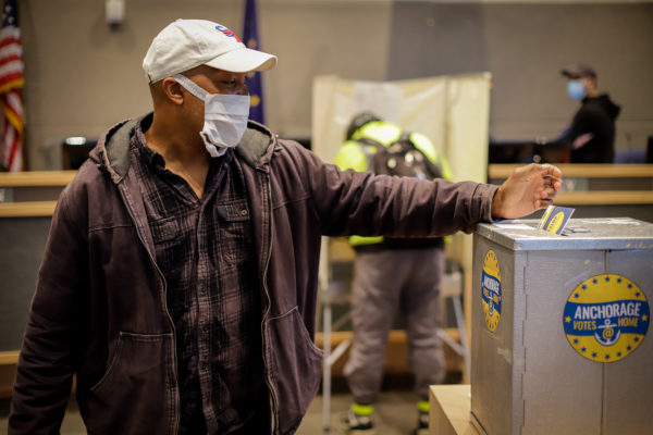 a person drops a ballot into a secure ballot box.