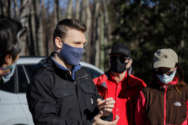 a person with a mask on talks with other people with masks on in a parking lot