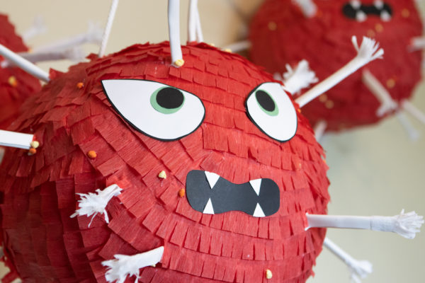 a red piñata with eyes and a mouth made to look like the COVID virus