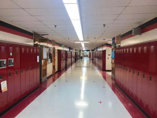 An empty hallway lined with red lockers.