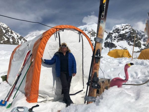 A woman stands outside a tent in a snowy area